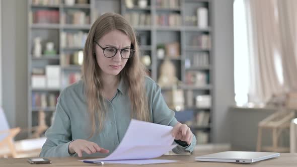 Disappointed Woman Writing On Paper While Sitting in Office