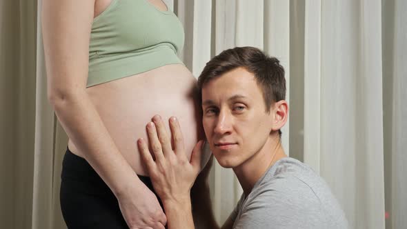 Man Strokes and Listens to Unborn Baby in Stomach of Wife
