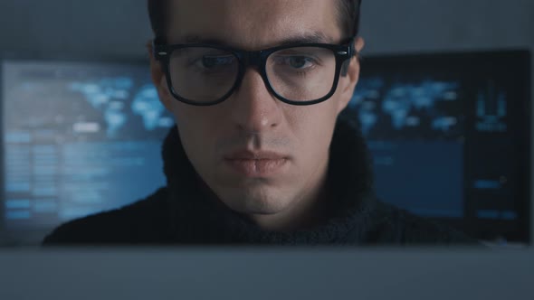 Close Up Portrait of Hacker Programmer in Eyeglasses Working at Computer at Background of Cyber
