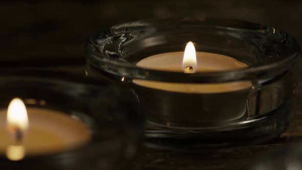 Tea candles with flaming wicks on a wooden background - CANDLES 010