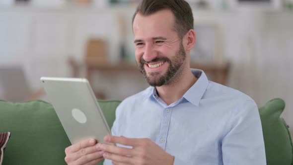 Young Man Celebrating Success on Tablet