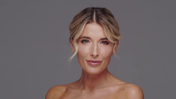 Studio portrait of young and beautiful blond woman over grey background.