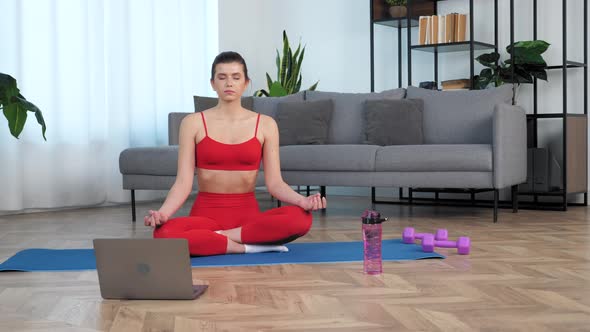 Calm Sportive Young Woman in Sportswear Practices Yoga at Home in Living Room