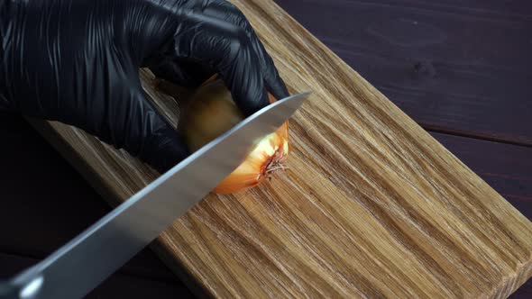 Chef Cuts Fresh Onions with Old Knife Into Pices on Wooden Cutting Board