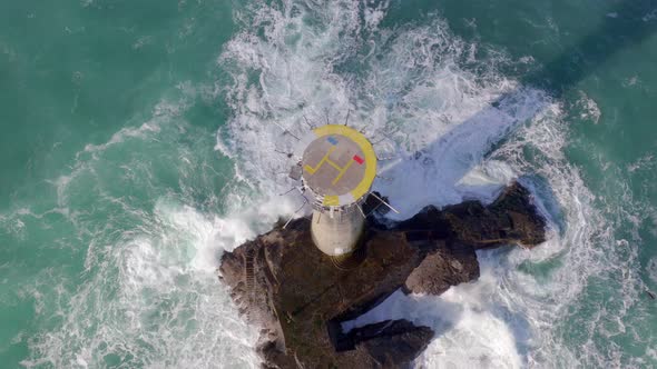 Lighthouse on a Rock in the Sea with Crashing Waves and a Helipad