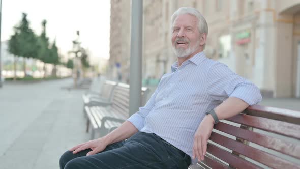 Old Man Smiling at Camera While Sitting on Bench