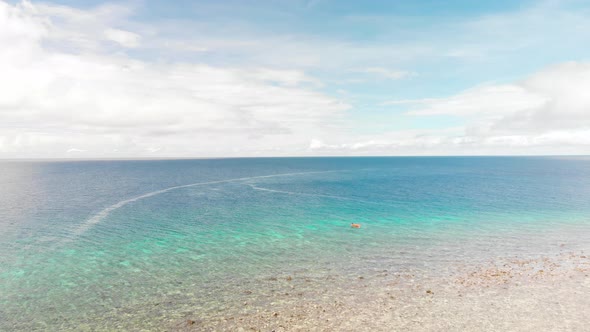 drone flying over fishing pump boat in a tropical open bright blue ocean under fluffy white clouds a