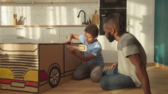 Loving African Dad and Son Creating Diy Car Toy From Cardboard at Home