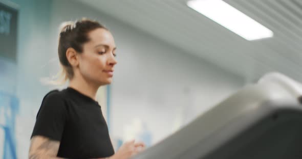 Young Woman Running on a Treadmill at Gym