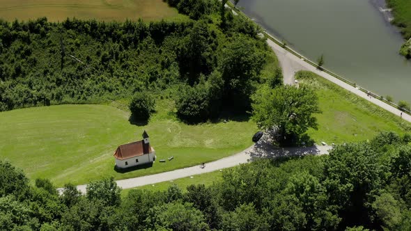 Aerial view at a little church in a green environment and a sportive biker is passing by the road at