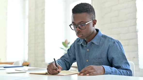 Serious Young African Man Doing Paperwork in Office