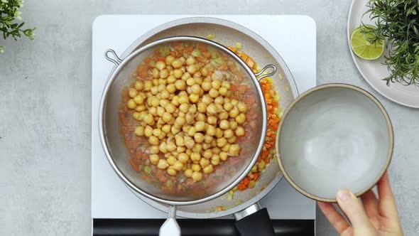 Anonymous person adding chickpea water into vegetables