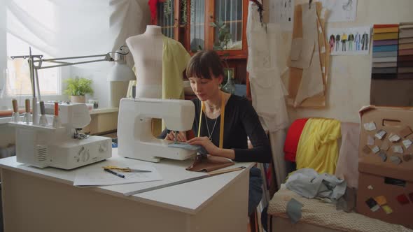 Woman Stitching Fabric on Sewing Machine in Dressmaking Studio