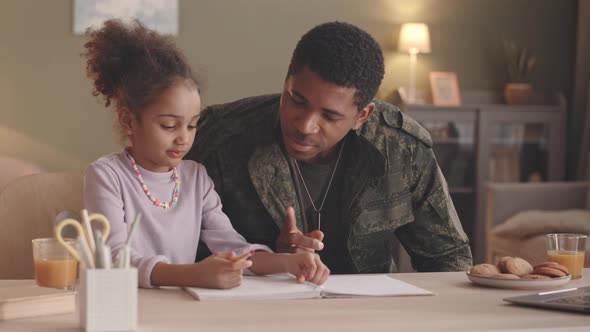 Soldier and His Little Daughter Doing Homework Together alt