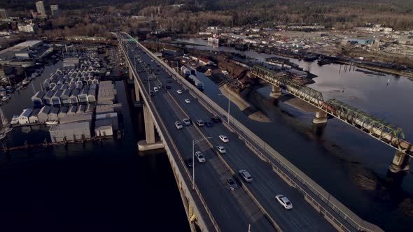 Cars driving on Ironworkers Memorial Bridge and train passing on Second Narrows rail, Vancouver in C