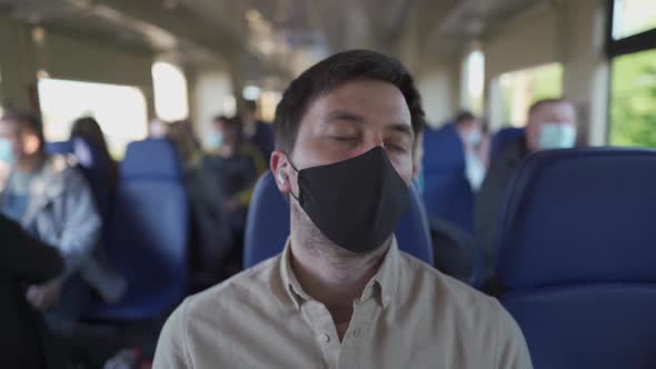 Male Passenger in Headphones and Protective Mask with Closed Eyes Relaxing on Subway