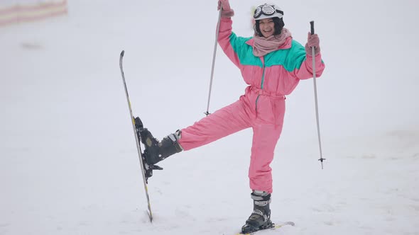 Joyful Caucasian Slim Woman Grimacing Standing on Skis Gesturing with Ski Poles