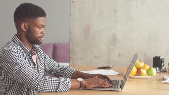 Young American Male Blogger Writing Article Using His Laptop