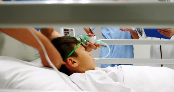 Nurse placing an oxygen mask and adjusting iv drip to patient in emergency room