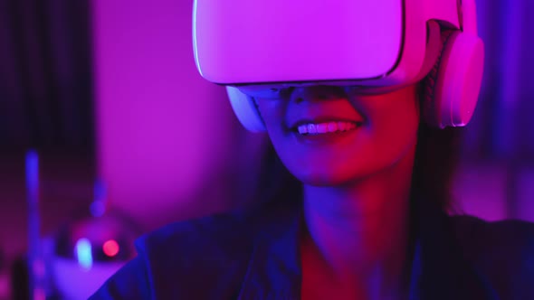 Young asian woman is using virtual reality headset. Neon light studio portrai