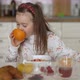 Girl Eating Fresh Orange During Breakfast - VideoHive Item for Sale