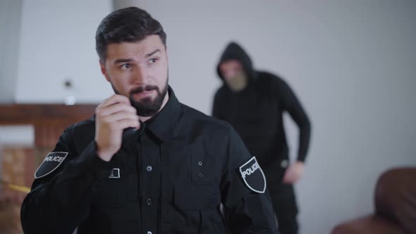 Portrait of Handsome Caucasian Police Officer Taking on Radio Set When Criminal Directing Guns