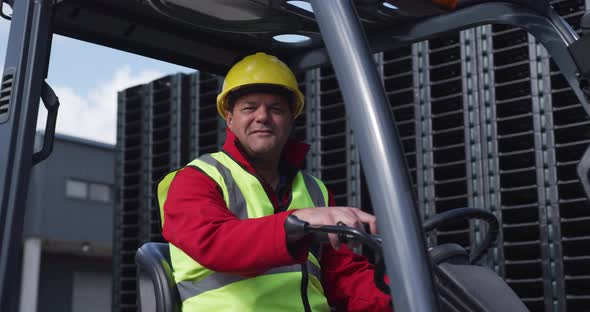 Warehouse worker driving forklift outside factory