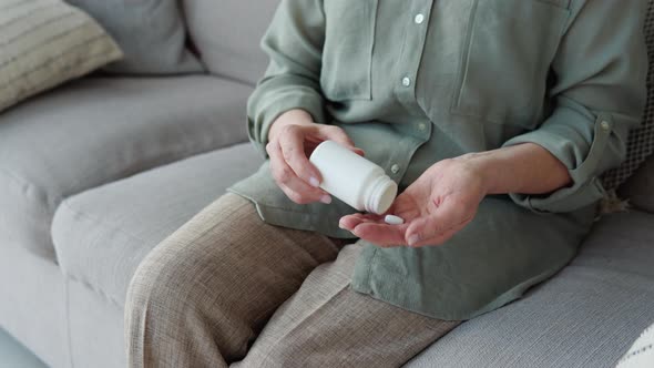 Senior Female Takes Pills Out of a Jar