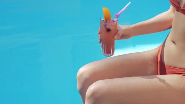 Close-up of Woman of Asian-looking Brunette in Red Stylish Fashionable Swimsuit Sits Poolside, Her