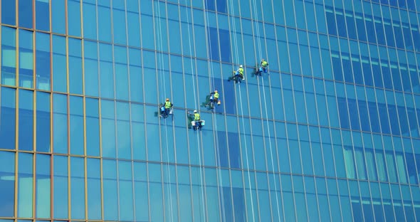 Five Men Workers in Red and Yellow Work Clothes Cleaning the Exterior Windows of a Business