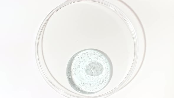 Transparent Cosmetic Gel Fluid Dripping Into the Glass Bowl of Petri