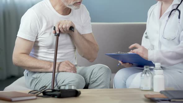 Senior Man Sitting on Sofa and Talking with Doctor, Healthcare and Illness