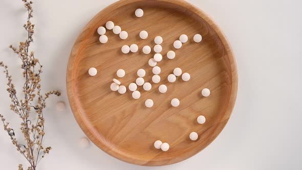 Vitamin or Medicine Falling in a Wooden Bowl