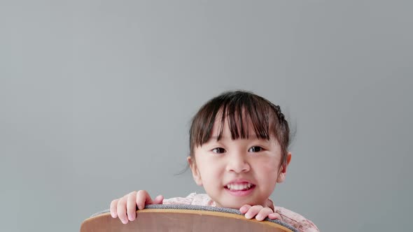 Cute Asian girl sitting on chair smile and tease with happiness in room. Kid teasing concept.
