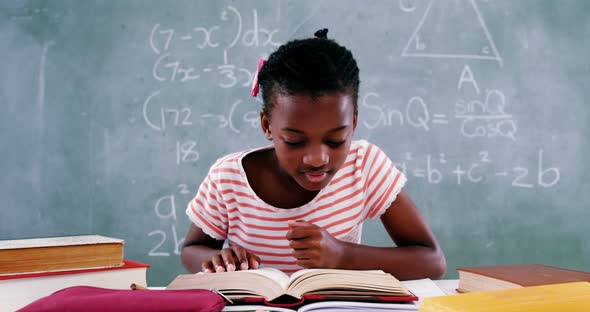 Schoolgirl reading book in classroom