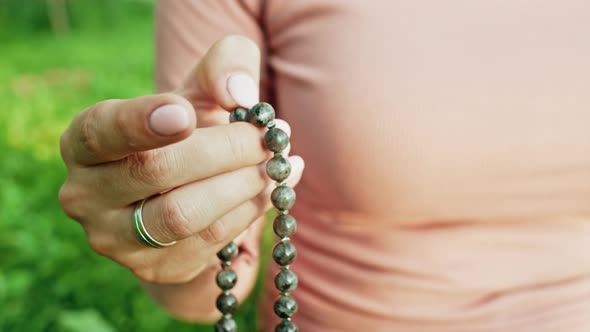 Woman Lit Hand Close Up Counts Rosary - Malas Strands of Gemstones Beads Used for Keeping Count