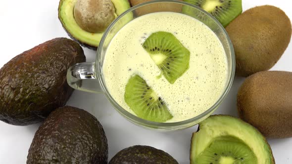 Kiwi, avocado and smoothie in a glass cup are on white table