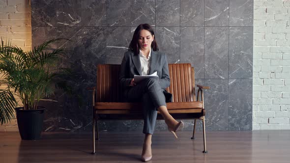 Worried Lady in Classic Suit Sits on Bench and Holds Papers
