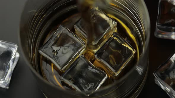 Pouring Whiskey, Cognac Into Glass with Ice Cubes. Pour of Alcohol Drink