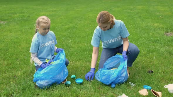 Schoolgirl and Mother Collecting Rubbish in Park, Earth Pollution, Ecosystem