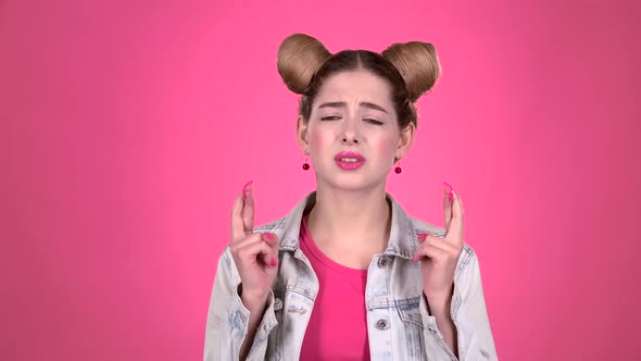 Girl Crossed Her Fingers. Pink Background. Slow Motion