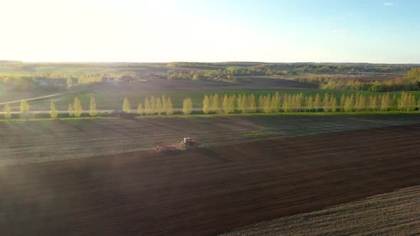 Aerial Flying Over Rural Village Fields Where Agriculture Tractor Plows The Land