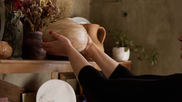 Side View Portrait of Contemporary Female Potter Putting Handmade Vase on Shelf in Studio Pleased