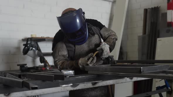 Professional welder in protective helmet in workshop