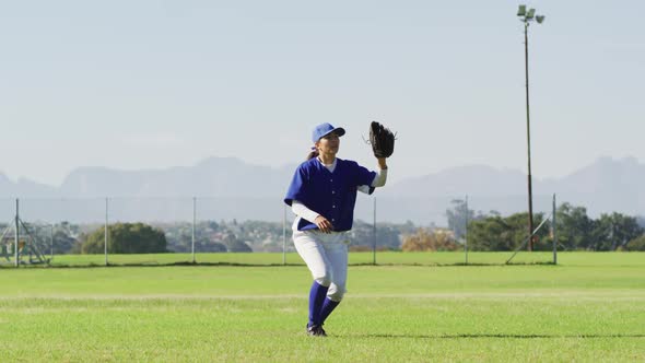 Caucasian female baseball player, fielder jumping, catching and throwing ball on baseball field