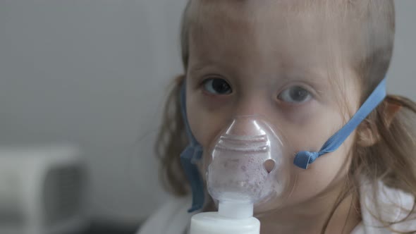 Cute little girl in the mask of an inhaler. Procedure of inhalation at home.