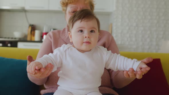 Happy Caucasian Grandmother Playing and Holding Her Little Granddaughter at Home