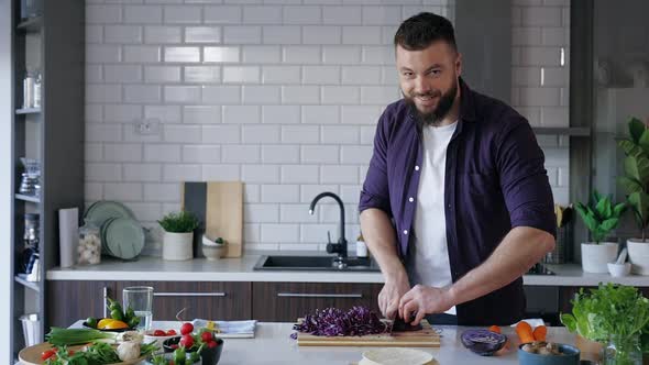 Young Man Chopping Vegetables in the Kitchen and Smiling, Copy Space, Slow Motion
