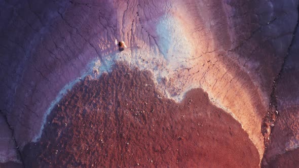 Overhead View of Woman Walking By Cinematic Pink Purple Desert Surface at Sunset