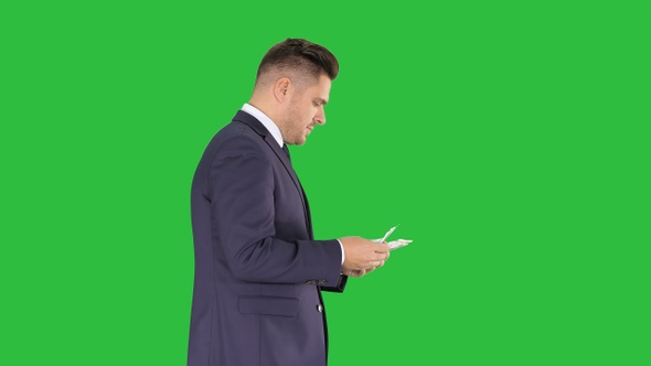 Rich man counts the money walking on a Green Screen, Chroma Key.